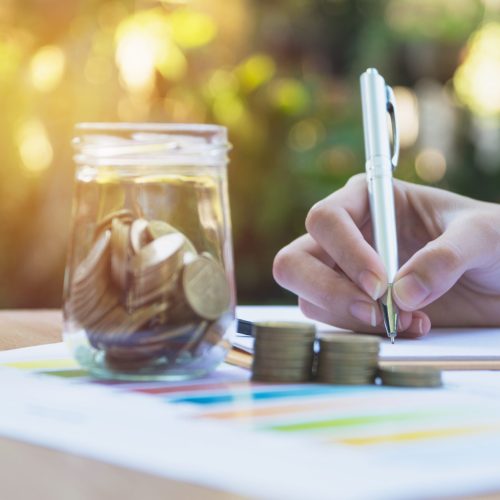 Businesswoman writing and analyzing for business with stack coin Businesswoman writing and analyzing for business with stack coins on the table. Financial analyzing and success concept.